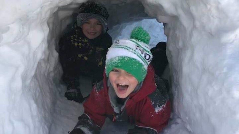 Deux jeunes sont dans un fort de neige.