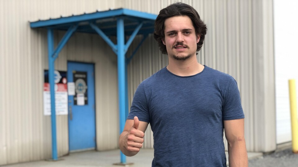 Phil Caron en t-shirt davant la porte du centre d'entraînement RHP Training Centre.