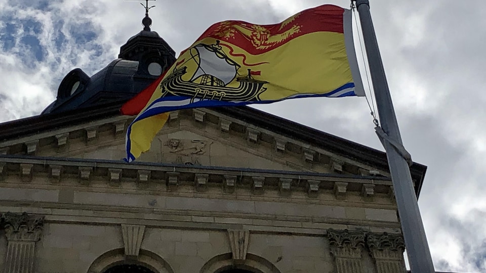 Gros plan sur le drapeau provincial devant l'édifice.