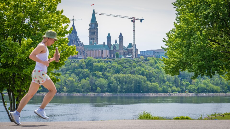 Le parlement du Canada vu de Gatineau alors qu'un coureur passe.