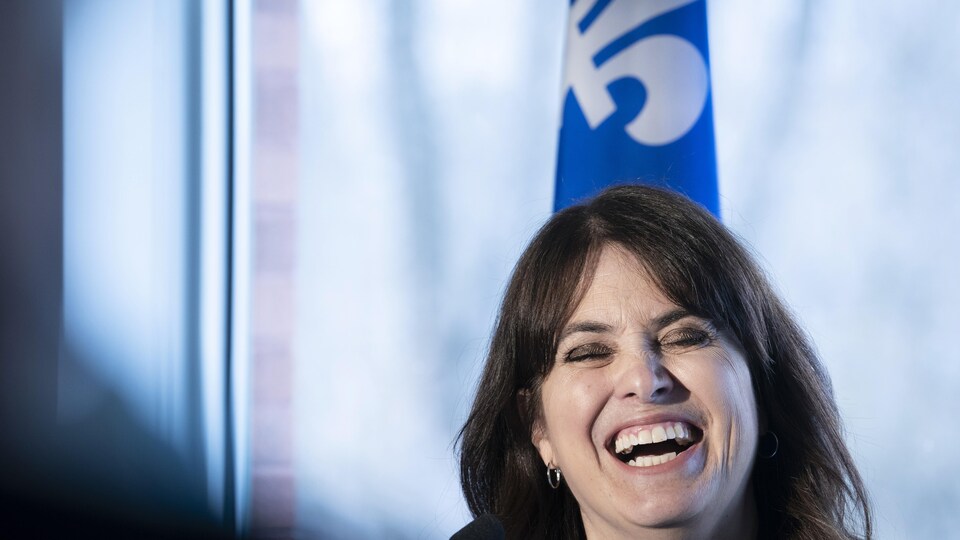 Véronique Hivon, laughing heartily, at a press conference in front of the lily.