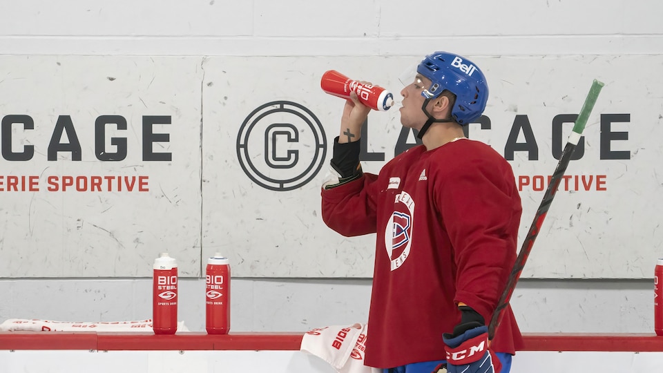 The hockey player takes a break to drink some water.