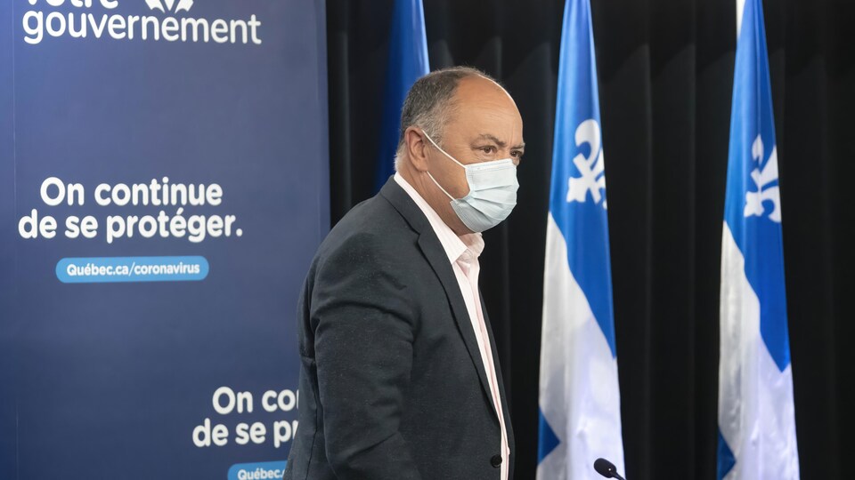 Le ministre Christian Dubé marche en portant un masque. 