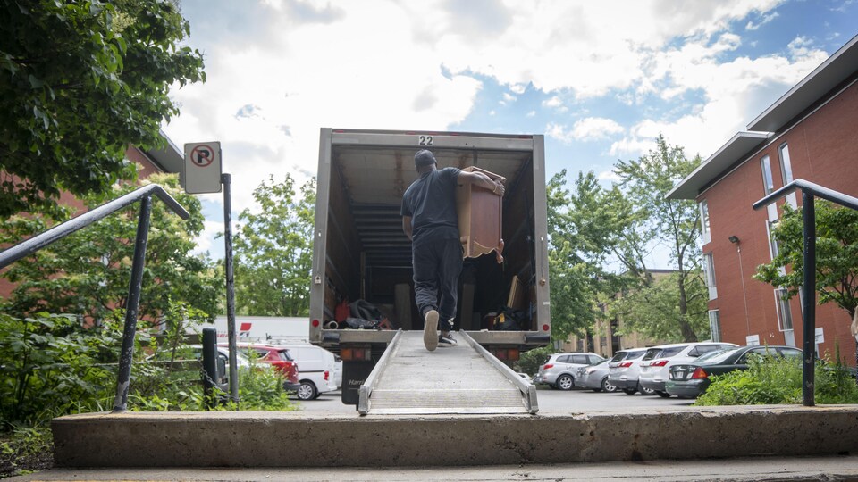 Un homme transporte un meuble dans un camion.