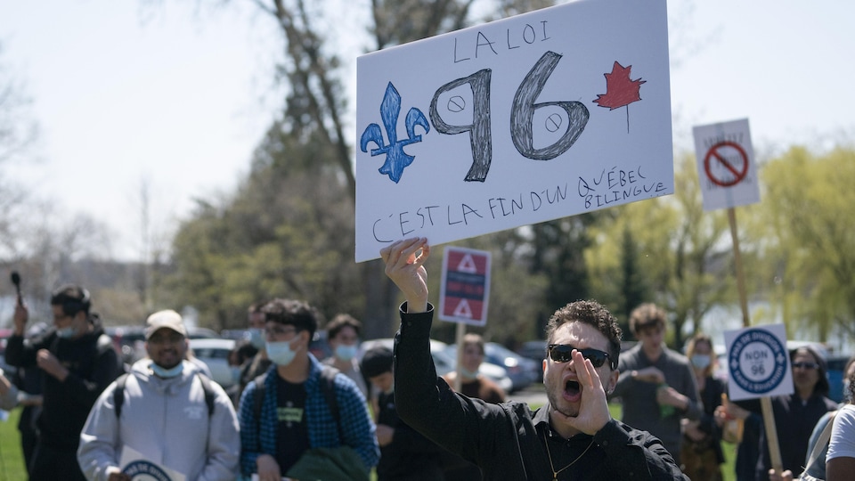Un jeune homme brandit une pancarte contre la loi 96