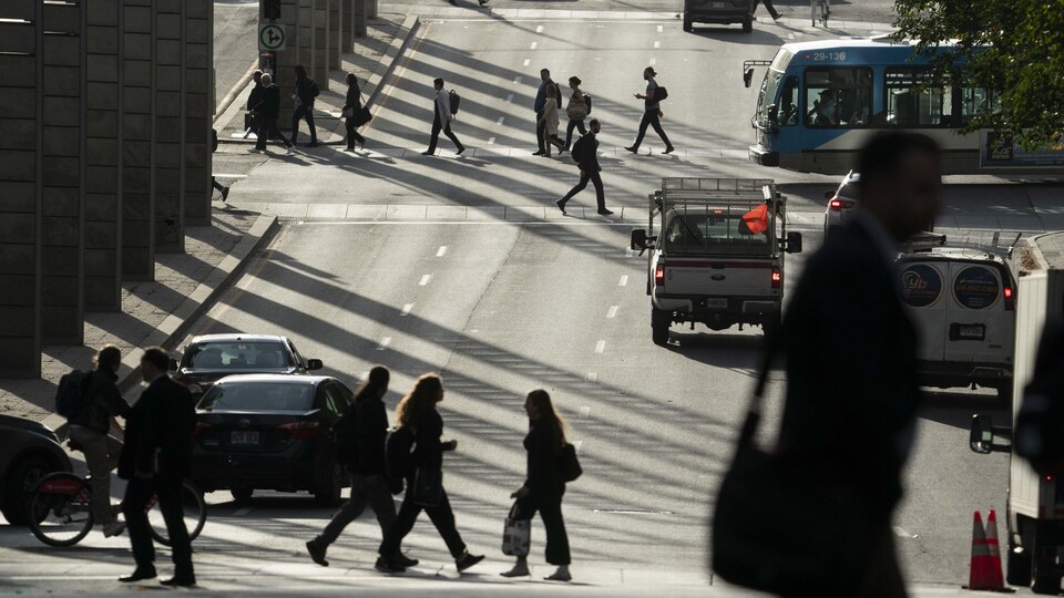 Des personnes circulent à pied, à vélo, en voiture et en autobus dans un quartier central de Montréal.