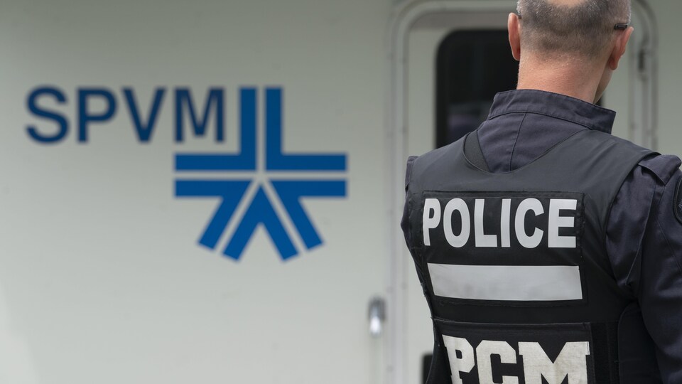 Un policier de dos devant un camion du SPVM.