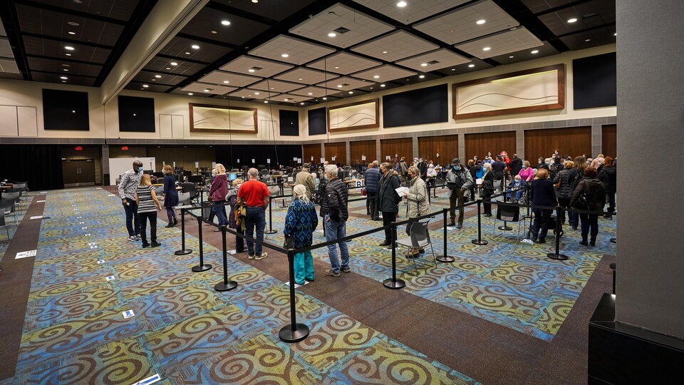 Dans une grande salle du palais de congrès, une file de résidents présents pour recevoir leur vaccin.