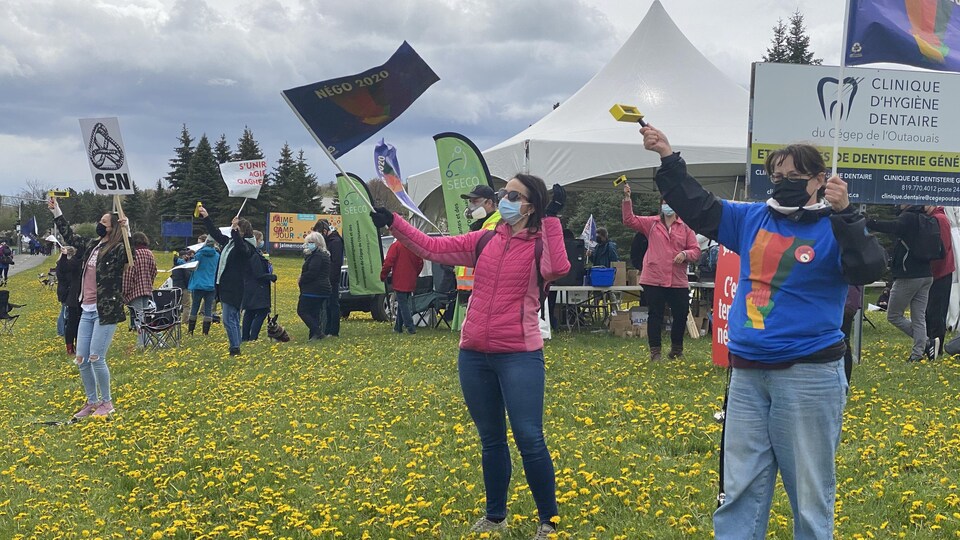Des personnes portant un masque brandissent des drapeaux.