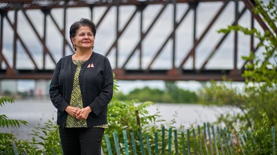 Une femme pose devant un pont.