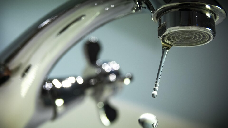 Une goutte d'eau tombe d'un robinet.