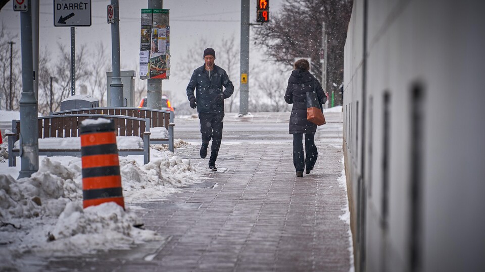 Un homme fait son jogging au centre-ville d'Ottawa sous de légers flocons.