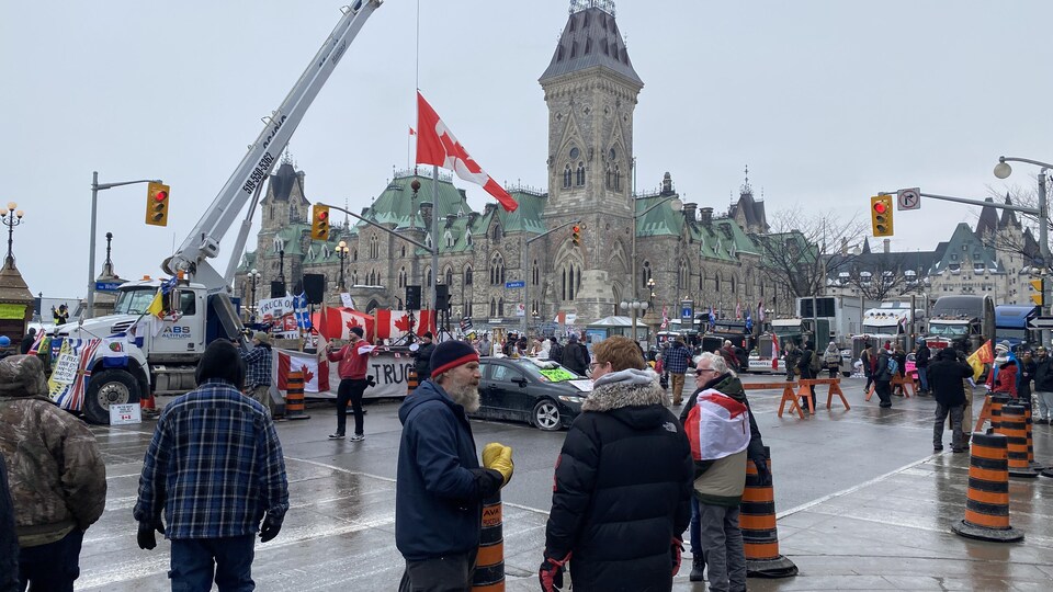 Des manifestants et des camions devant le parlement du Canada.