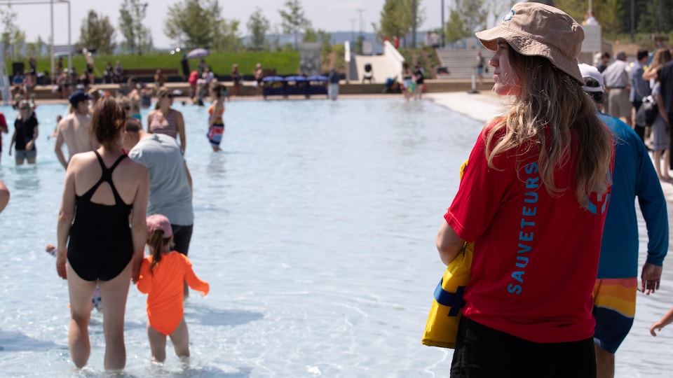 People with their feet in the water at the new swimming pool on the Promenade Samuel-de-Champlain.