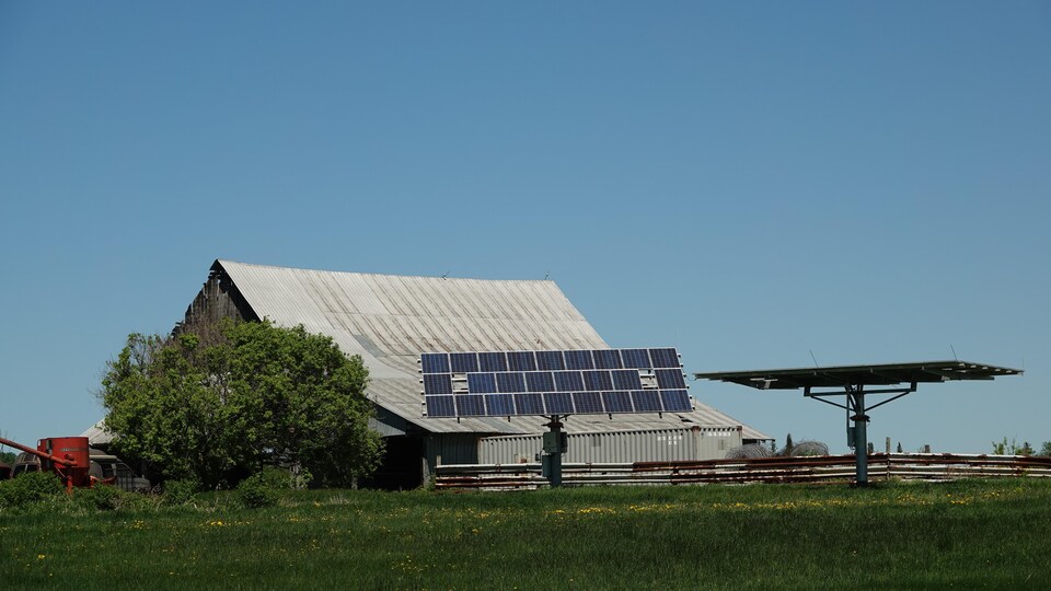 Des panneaux solaires devant une grange. 