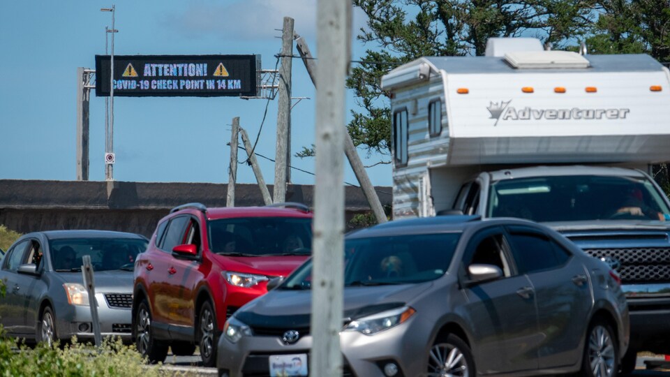 Des autos font la file. En arrière, on voit un tableau de signalisation numérique sur le pont de la Confédération.