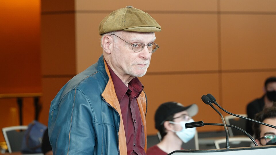 A man wearing a cap speaks into the microphone.