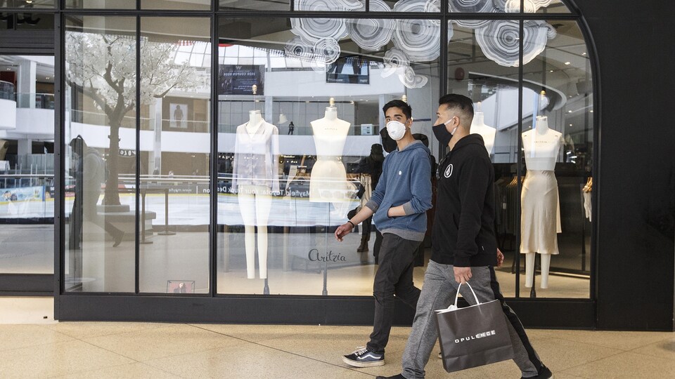 Deux jeunes portant un masque dans un centre commercial.