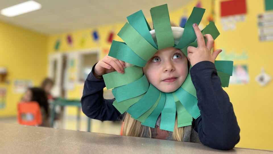 Une enfant porte un bricolage en forme de fleur autour de la tête.