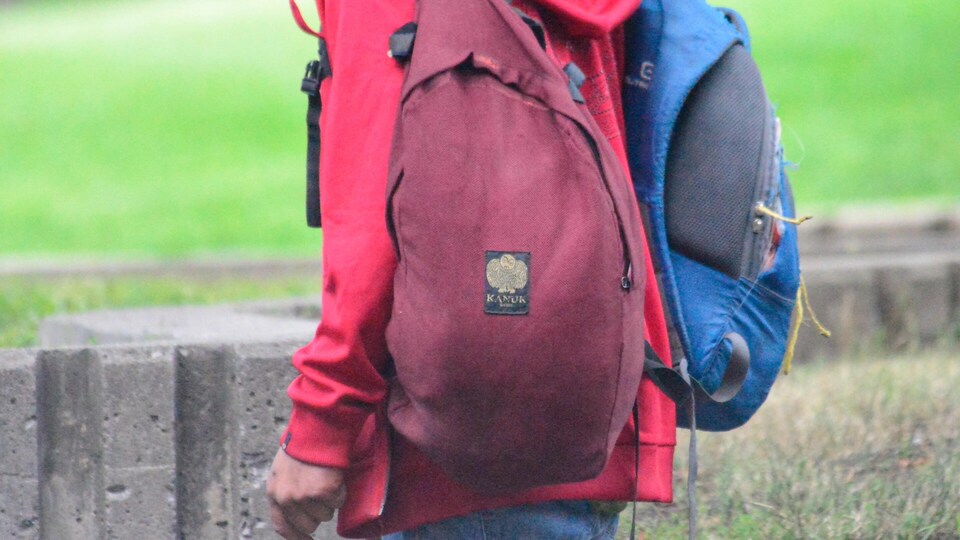 Sans-abri marchant avec deux sacs à dos troués