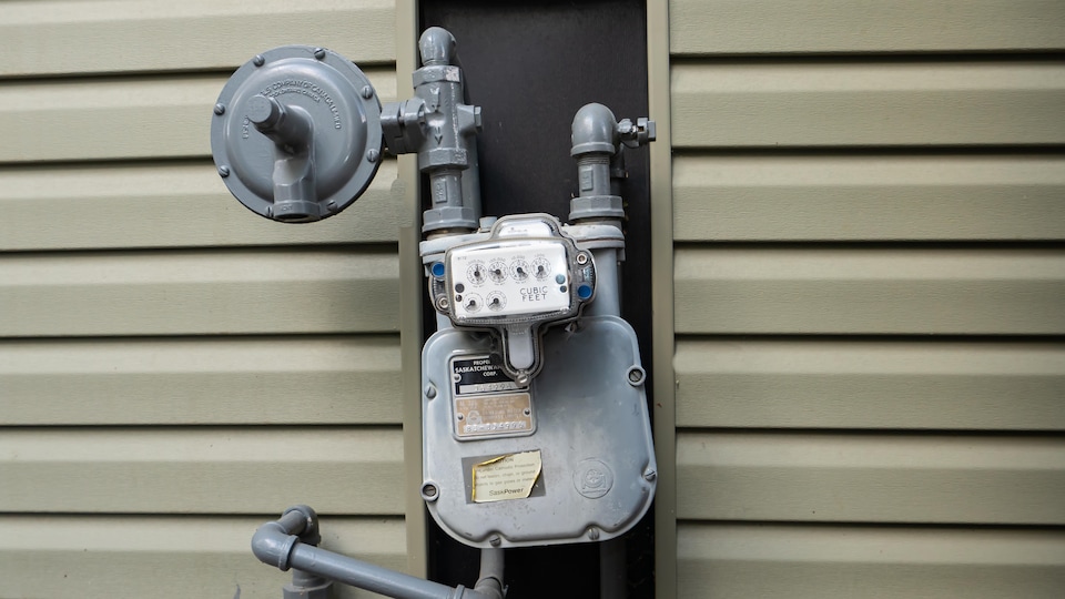 Un compteur de gaz naturel fixé à un mur extérieur d'une maison.