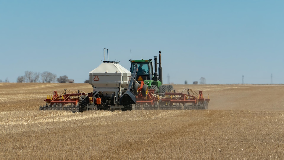 Un tracteur ensemence un champ.