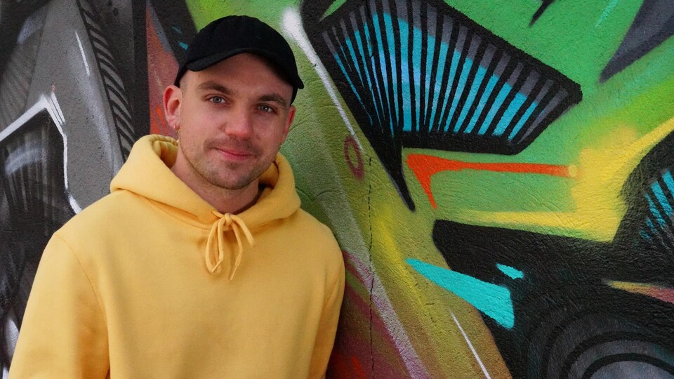 Le musicien fransaskois Shawn Jobin devant une murale à Saskatoon.