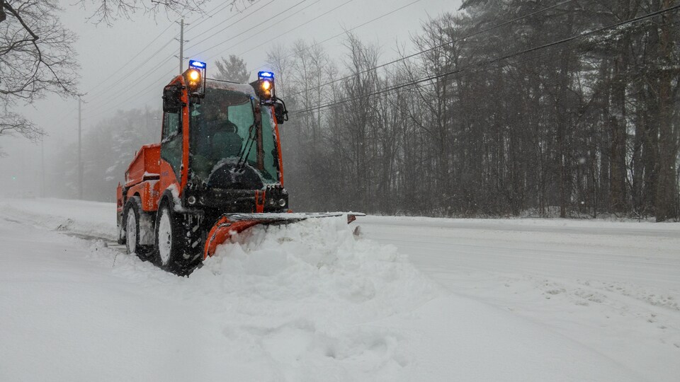 Une petite déneigeuse déblaie les trottoirs lors d'une tempête de neige.