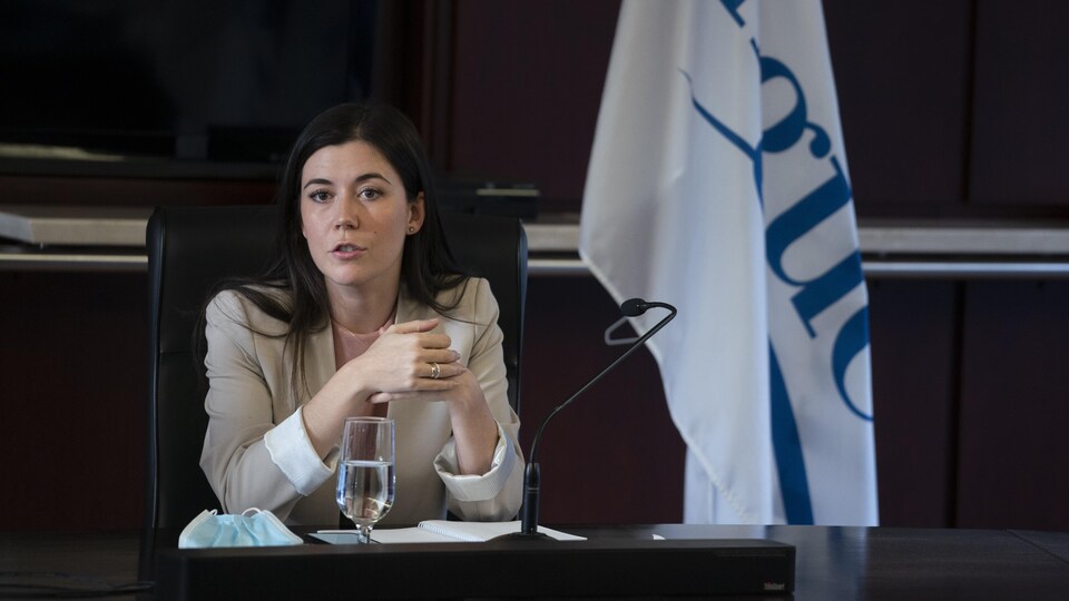 Catherine Fournier, seule, assise à un bureau.