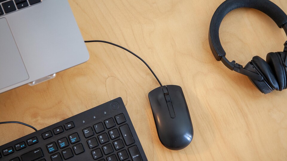 Un bureau de travail, avec ordinateur, clavier, souris et écouteurs