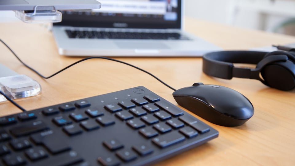Un ordinateur portable, un clavier, une souris et un casque d'écoute ont déposé sur une table.