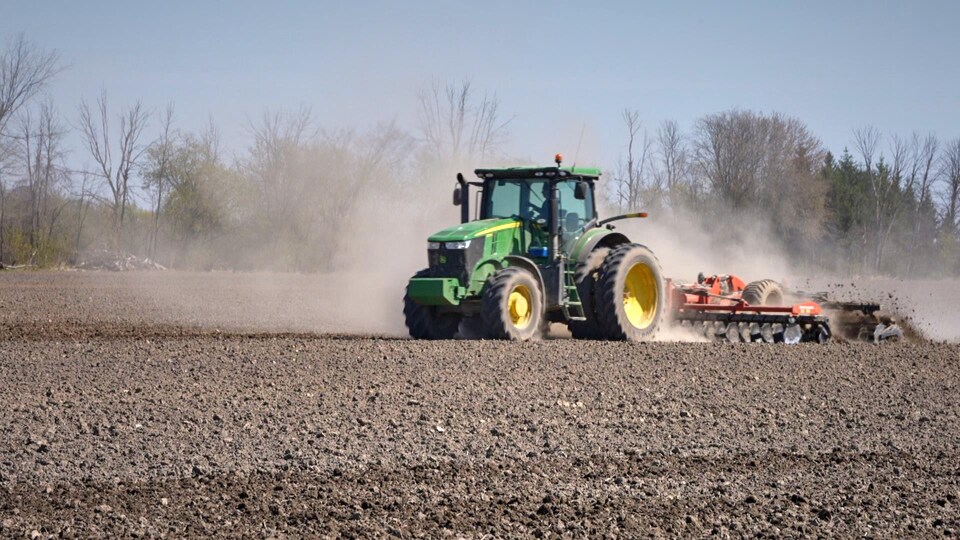 Agricultural worker plowing a field with a tractor.