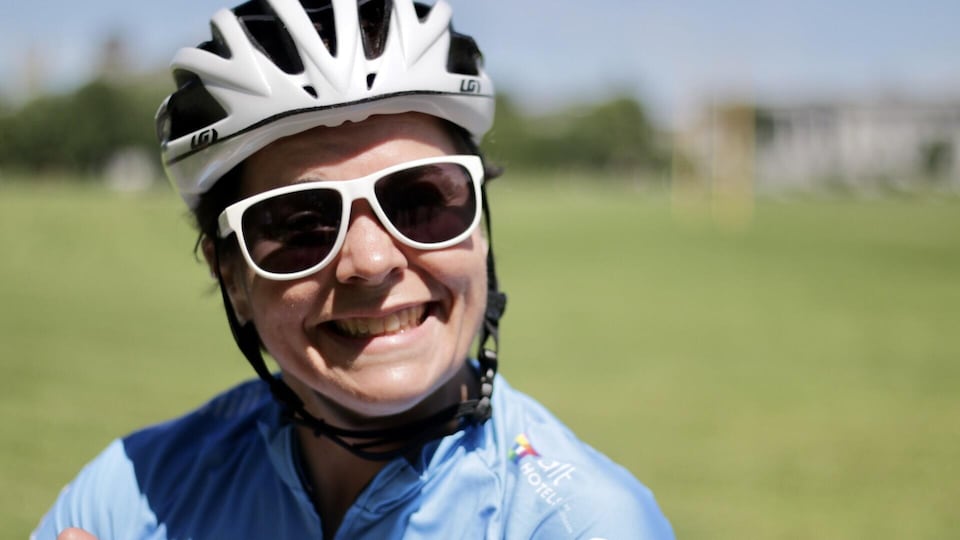 Marie-Ève Croteau sourit avec ses lunettes de soleil et son casque de vélo.