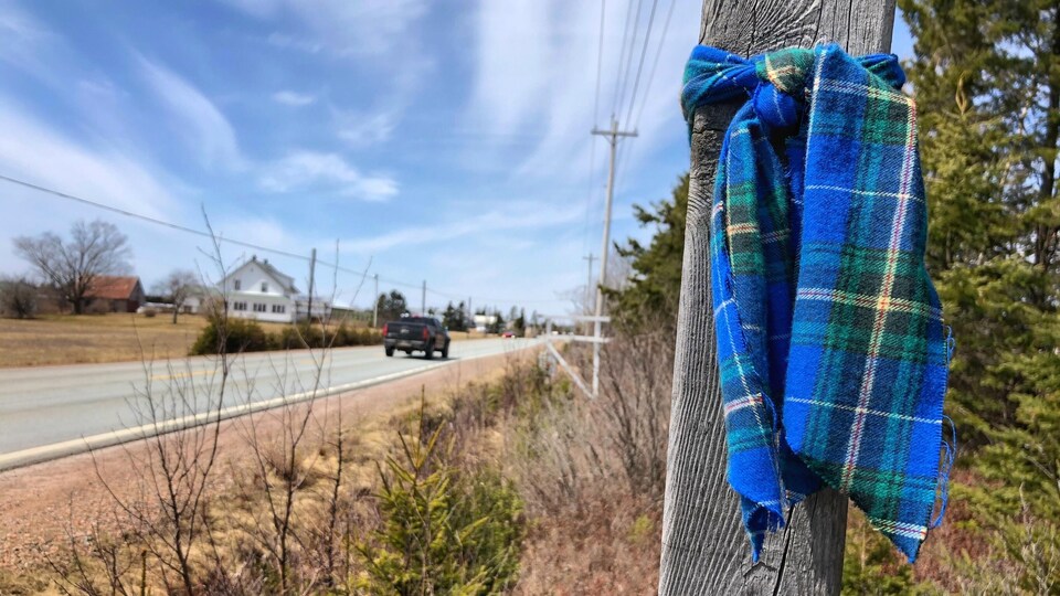 Tartan bleu et vert noué à un poteau le long d'une route rurale.
