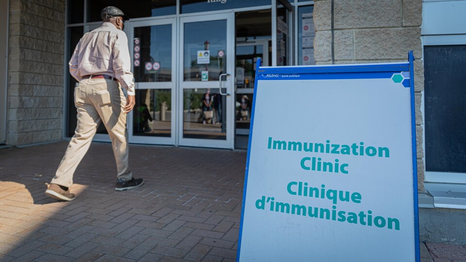 Une personne se dirige vers un édifice où il est inscrit clinique d'immunisation.