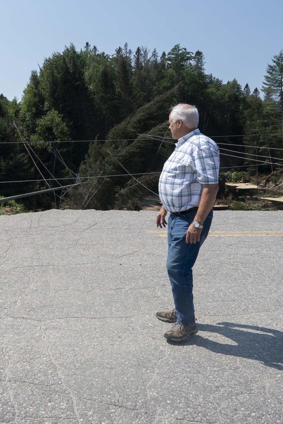 Le maire de L'Ascension, Jacques Allard, constate l'étendue des dégâts, au bord d'une large crevasse qui coupe une route en deux.