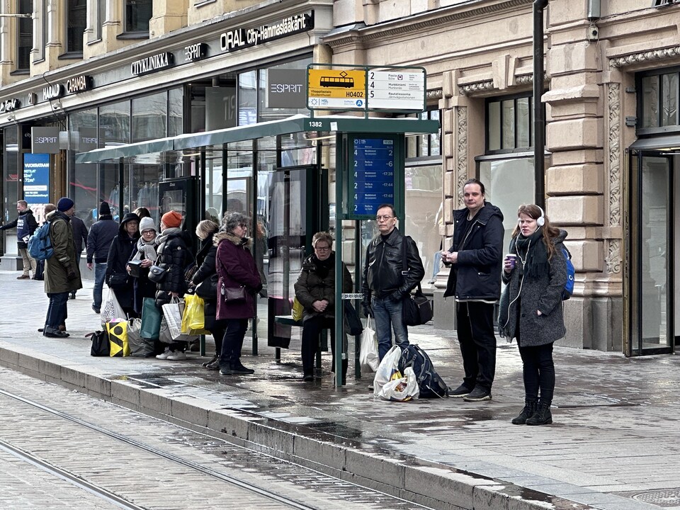 Des Finlandais attendent le tramway sur le bord des voies.