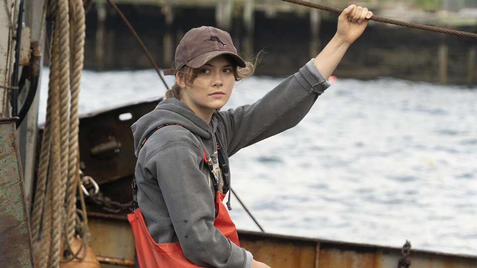 Une jeune femme est sur un bateau de pêche.