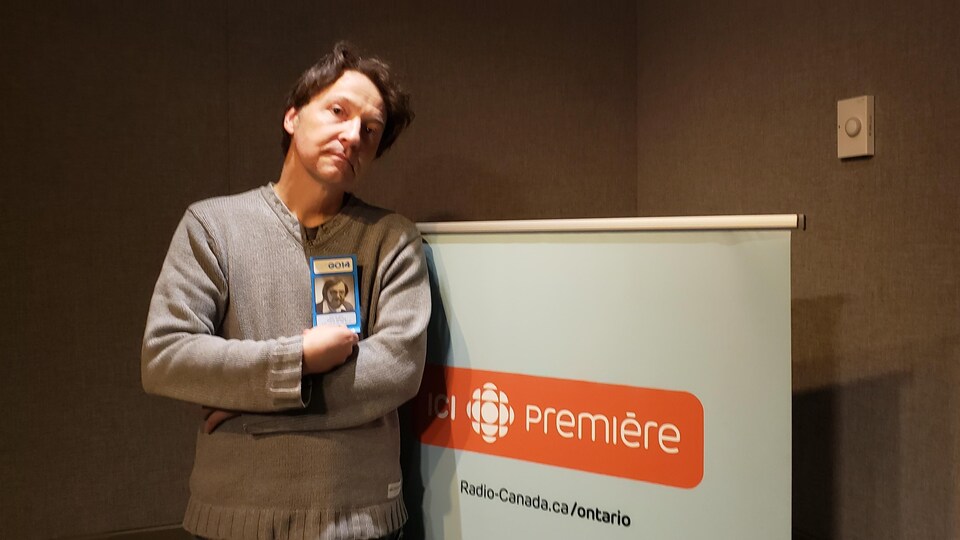 Dominique Denis en studio à ICI Toronto. Il porte dans ses mains une copie d'un palmarès des années 70.