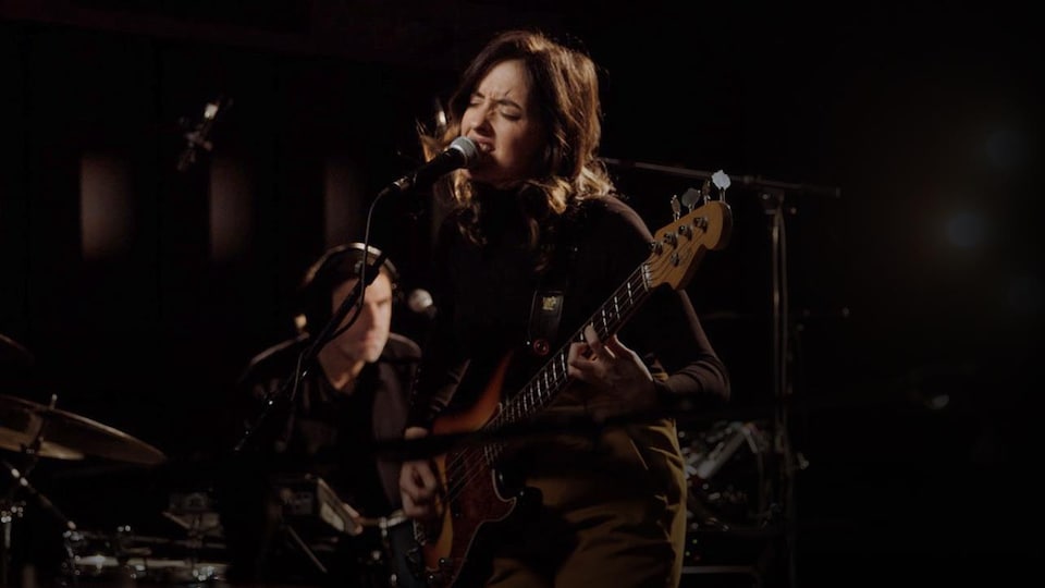 La chanteuse en prestation, les yeux fermés, sa basse dans les mains.