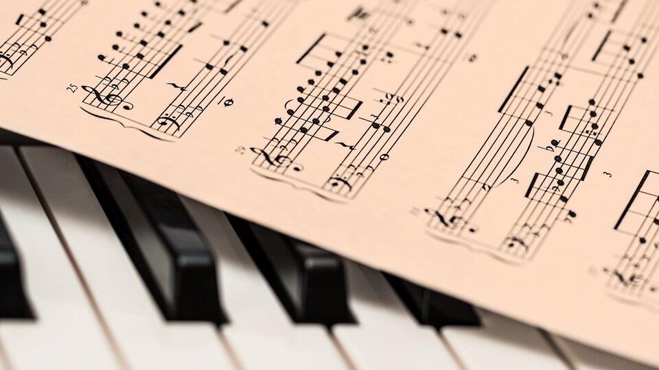 Gros plan sur des partitions de musique classique qui ont été déposées sur un clavier de piano.