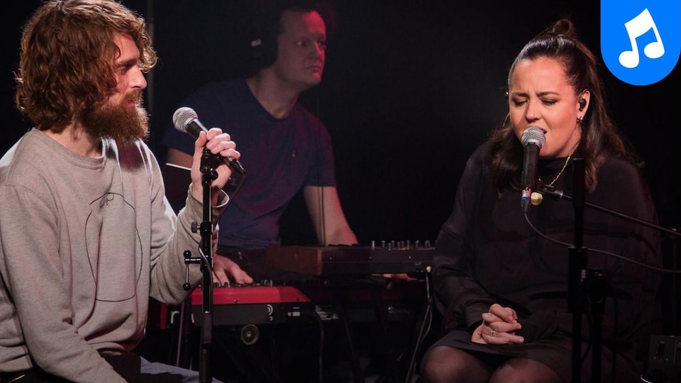 Ariane Moffatt et Philippe Brach assis l'un à côté de l'autre sur scène devant un claviériste; ils chantent.