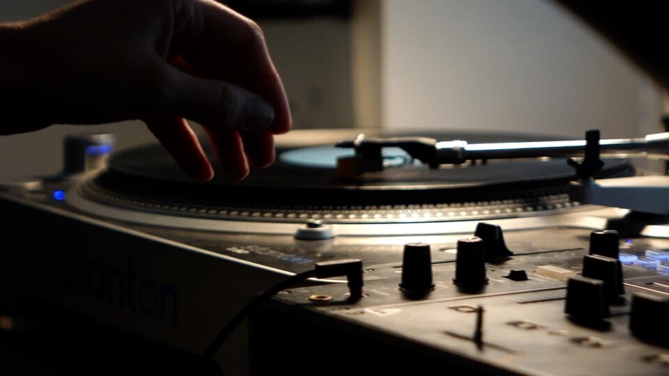Une main au-dessus d'une plaque tournante de vinyle.
