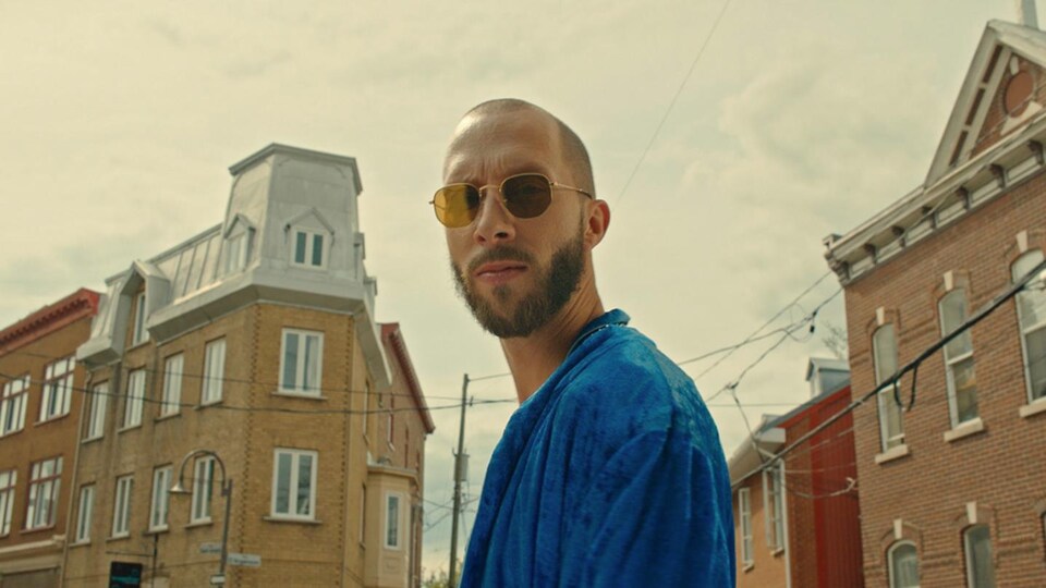 Le rappeur Eman pose dans une rue avec ses lunettes de soleil.