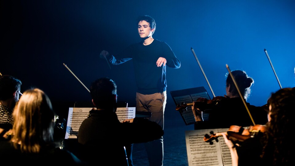 Le jeune chef d'orchestre Nicolas Ellis en train de diriger un orchestre dans les studios de Radio-Canada