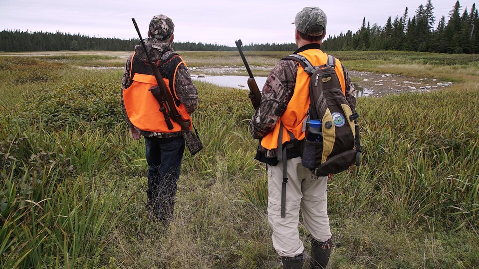 Deux chasseurs guettent l'horizon dans une clairière.