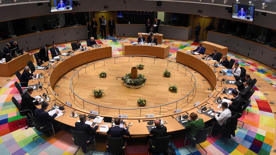 Dans un parlement, des députés sont assis sur une table circulaire.