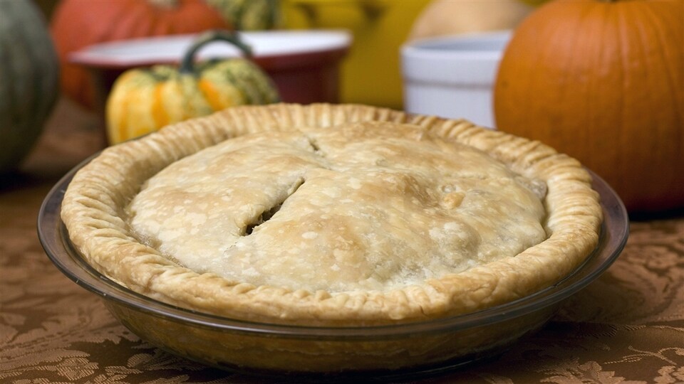 Une tourtière devant des potirons.