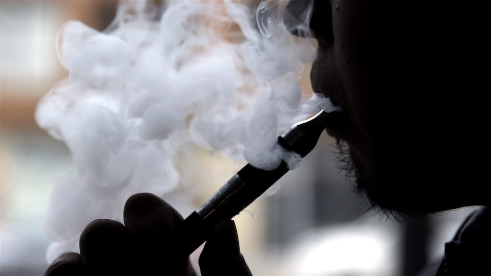 Un homme utilise une cigarette électronique.