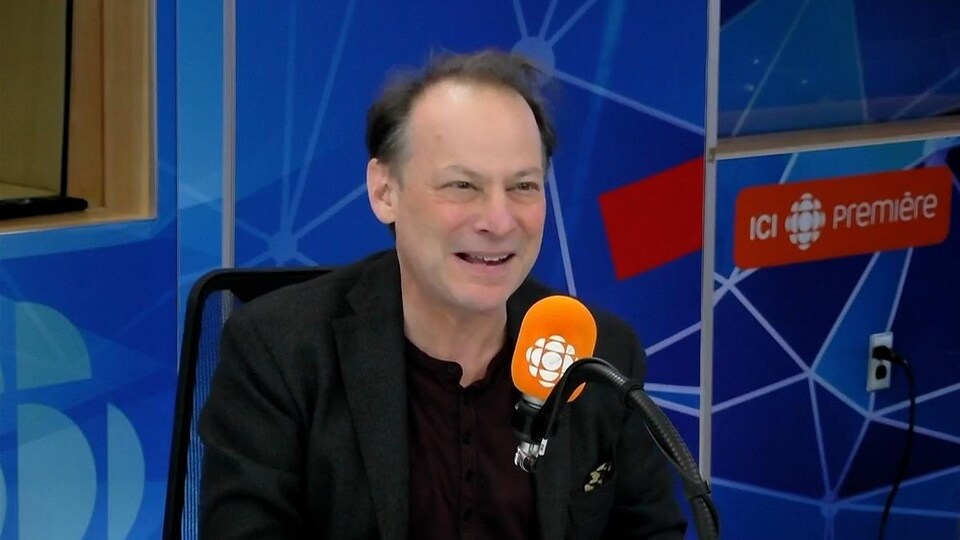 Adam Gopnik derrière un micro dans un studio radio de Radio-Canada.